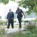 Dos agentes de policía uniformados patrullan un parque urbano al aire libre para garantizar la seguridad y protección del público.