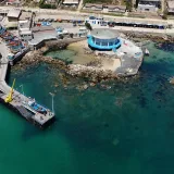 Fotografía aérea del muelle de Algarrobo con barcos pesqueros y edificios costeros, que muestra la vibrante escena costera de Chile.