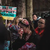 People rally in London to support Ukraine, expressing anti-war sentiments with signs and art makeup.