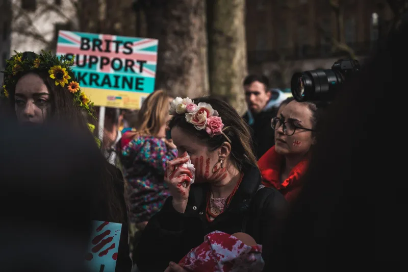 People rally in London to support Ukraine, expressing anti-war sentiments with signs and art makeup.