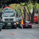 Vista de una calle con tráfico urbano, vehículos, motocicletas y un trabajador en la ciudad.