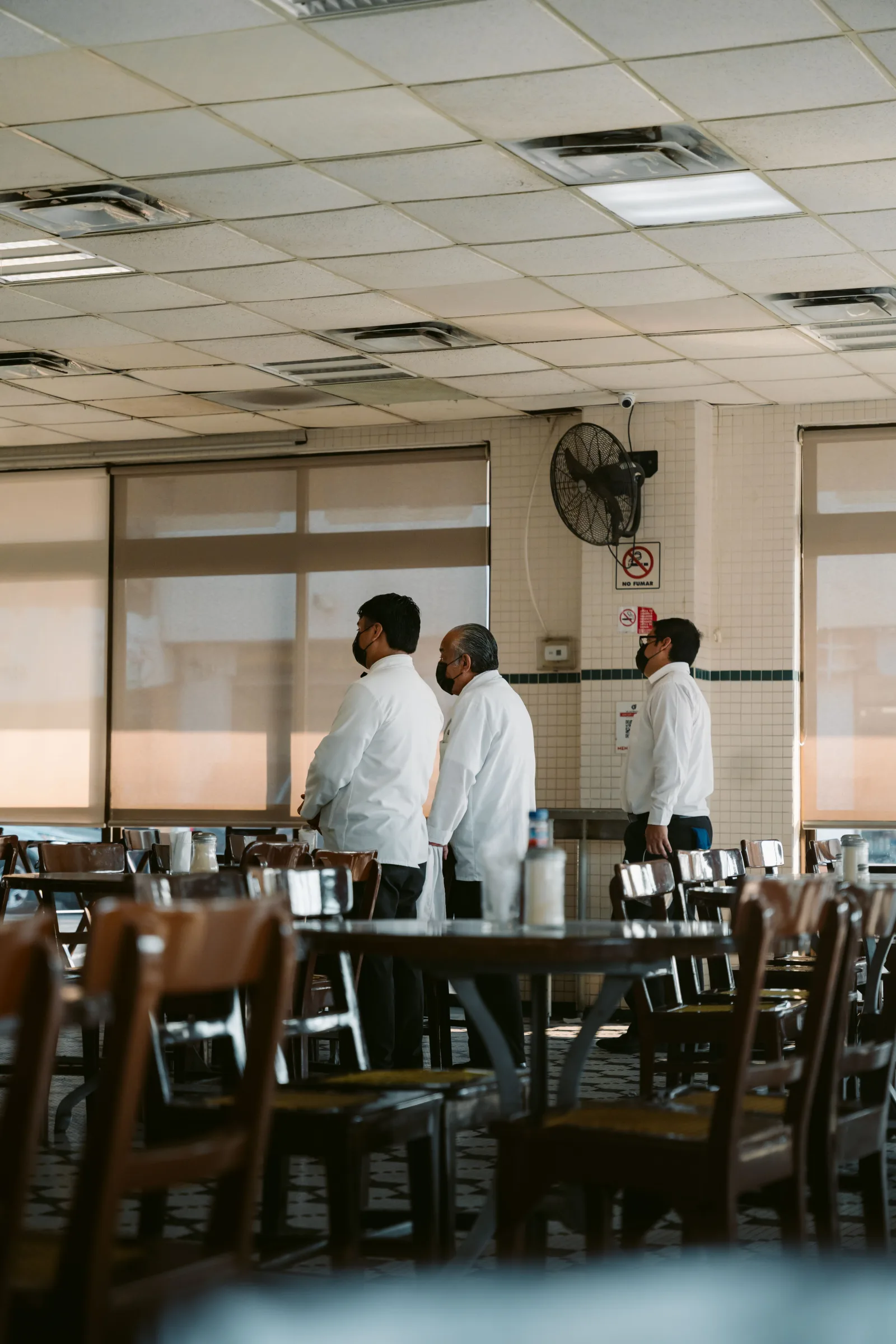 Tres camareros de pie en un restaurante de Veracruz, México, con uniformes blancos.