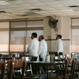 Tres camareros de pie en un restaurante de Veracruz, México, con uniformes blancos.
