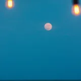 A serene view of the full moon over Lake Maracaibo with lights framing the scene.