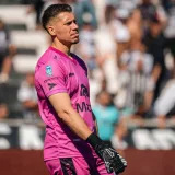 Soccer goalkeeper wearing a pink jersey focused during a lively outdoor match.