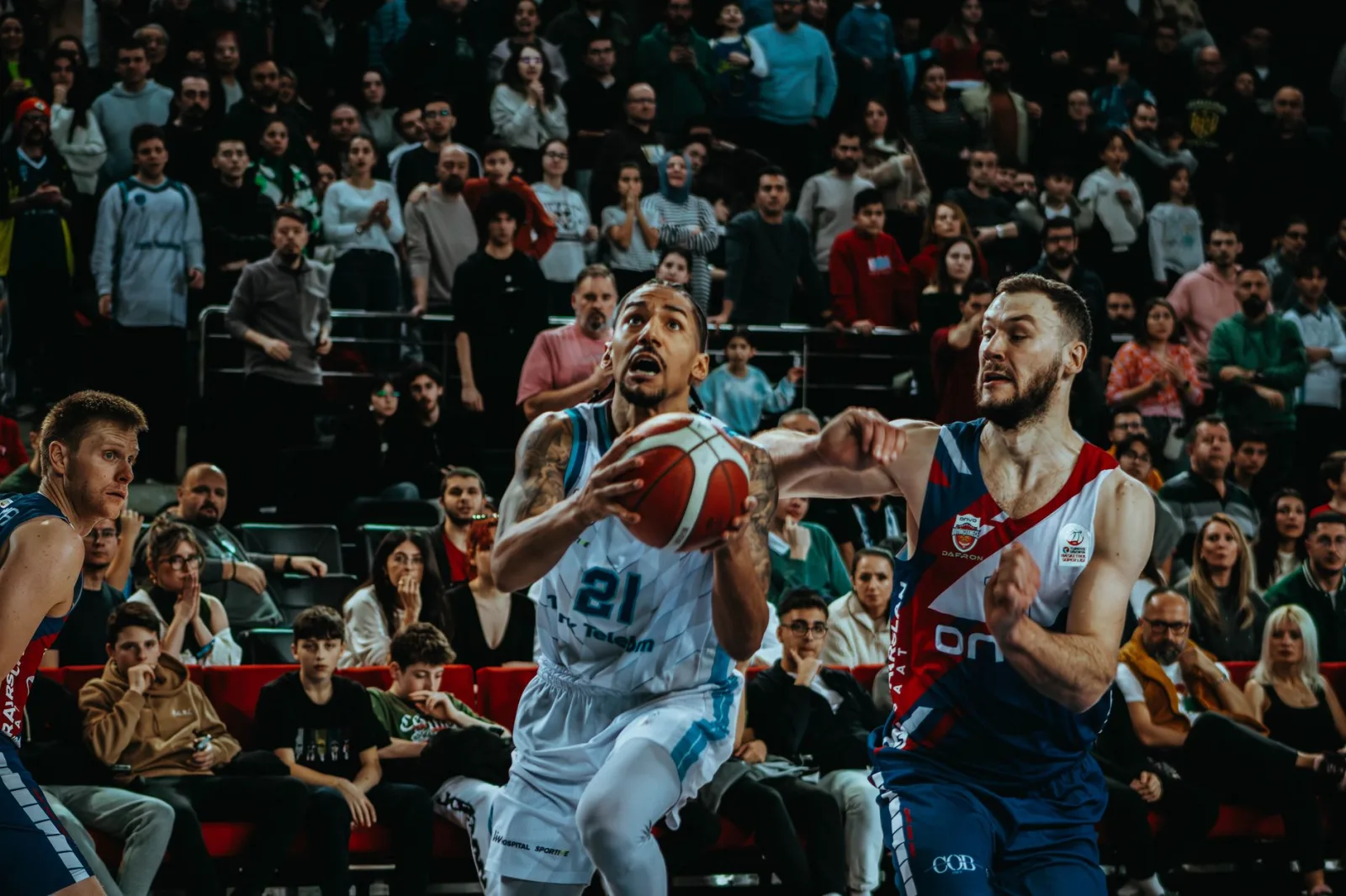 Toma de acción dinámica de un partido de baloncesto en vivo que captura la competencia y la participación del público.