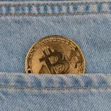 Primer plano de una moneda de bitcoin en un bolsillo de mezclilla, que simboliza las criptomonedas y las finanzas.