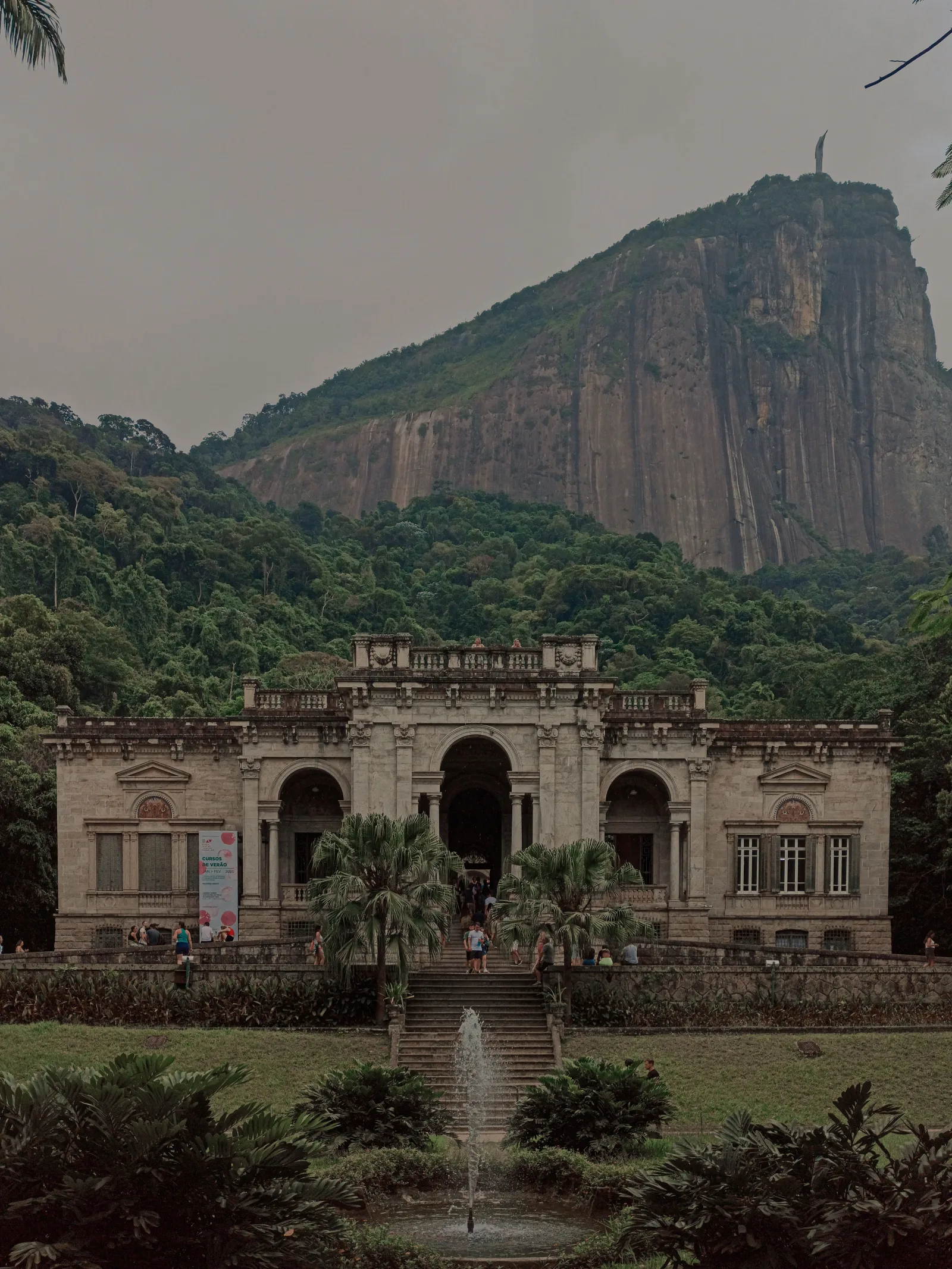 Aged building exterior with arches between mount with lush trees and fountain in Rio de Janeiro Brazil