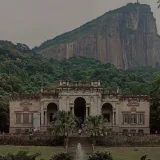 Aged building exterior with arches between mount with lush trees and fountain in Rio de Janeiro Brazil