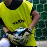 a young man holding a soccer ball in front of a net