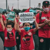 Protesters rallying against Bolsonaro in Rio de Janeiro, showing signs and wearing masks amidst the crowd.