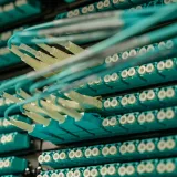 Vista detallada de cables de fibra óptica conectados a un rack de servidores, que muestra tecnología moderna.