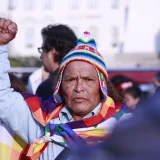 Un hombre mayor con vestimenta colorida levanta el puño durante un encuentro cultural en Perú.