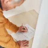 Senior man marking a ballot at a voting booth in an indoor polling station.