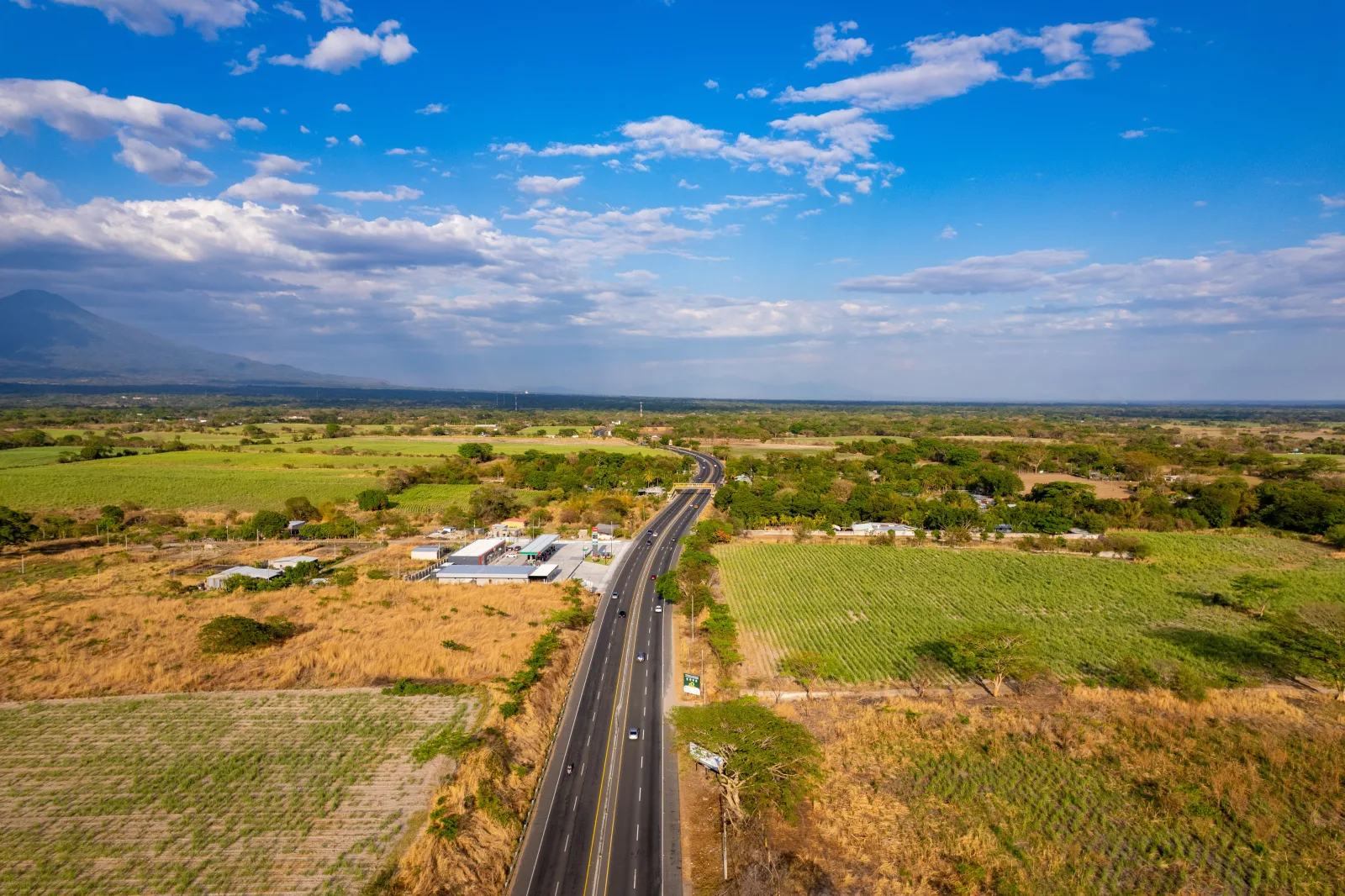 Scenic aerial view of a countryside road in El Salvador under a clear blue sky.