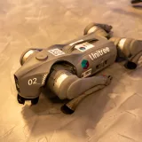 Un perro robot Unitree descansando en un suelo de concreto interior.