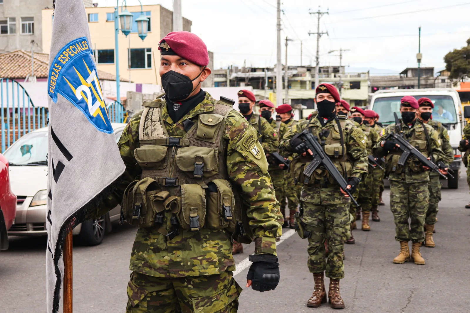 Soldados ecuatorianos con camuflaje y boinas participando en un desfile, demostrando disciplina militar.