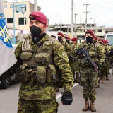 Soldados ecuatorianos con camuflaje y boinas participando en un desfile, demostrando disciplina militar.
