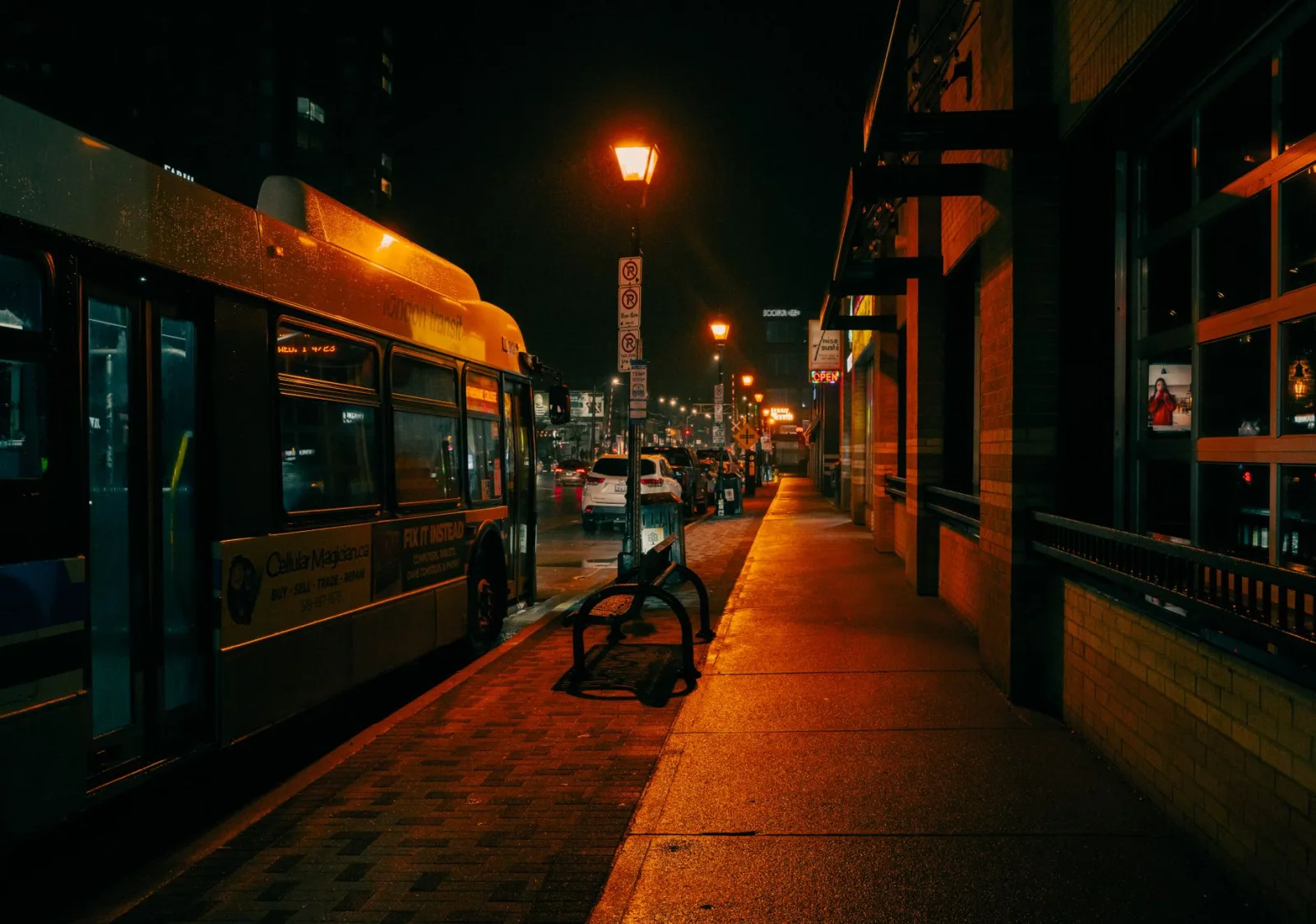 Un autobús estacionado en una parada bajo las brillantes farolas de London, Ontario, que muestra la vibrante vida nocturna de la ciudad.