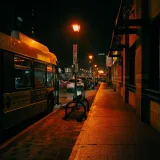 Un autobús estacionado en una parada bajo las brillantes farolas de London, Ontario, que muestra la vibrante vida nocturna de la ciudad.