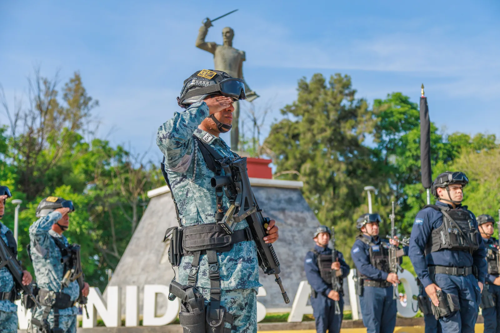 El personal militar en formación saluda cerca de un monumento histórico, enfatizando la disciplina y el patriotismo.