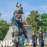 El personal militar en formación saluda cerca de un monumento histórico, enfatizando la disciplina y el patriotismo.