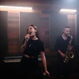 Energetic music band performing live in a recording studio with vocalist and saxophonist.