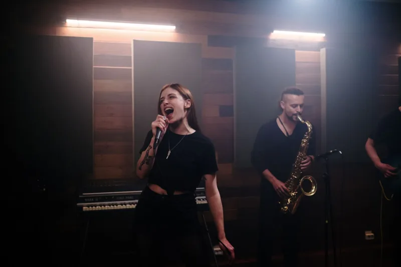 Energetic music band performing live in a recording studio with vocalist and saxophonist.