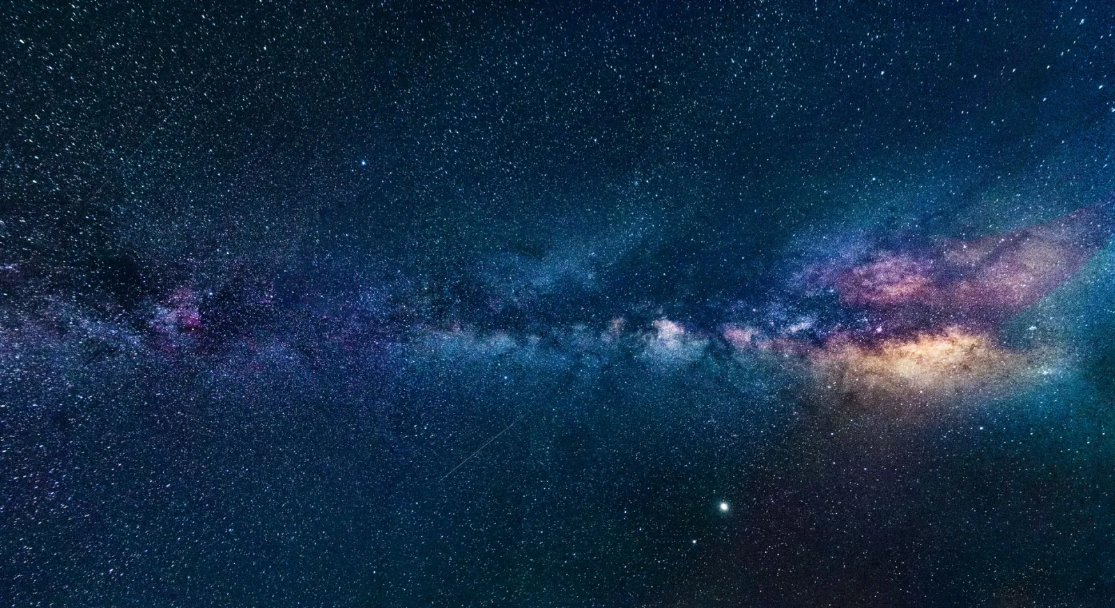Captura de la galaxia de la Vía Láctea extendiéndose a través del oscuro cielo nocturno, salpicado de estrellas.