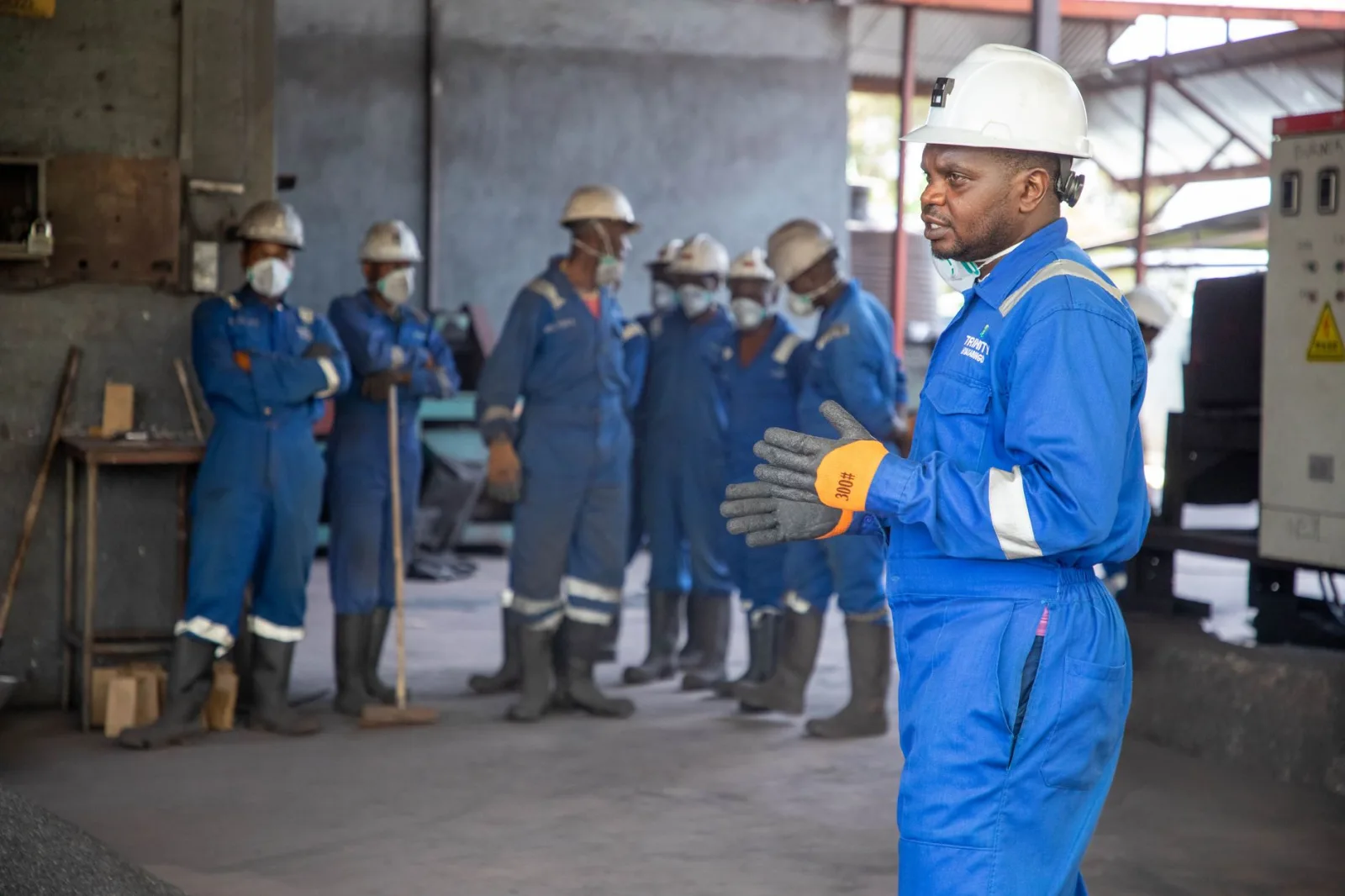 Un grupo de trabajadores de fábrica con equipo de protección recibiendo capacitación en interiores.
