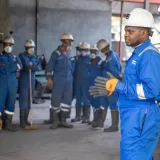 Un grupo de trabajadores de fábrica con equipo de protección recibiendo capacitación en interiores.