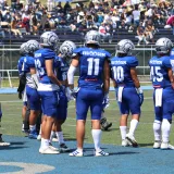 Equipo con uniformes azules reunido en un día soleado durante un partido de fútbol americano