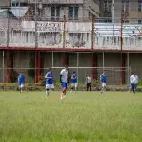 Amateur soccer players compete on an urban field in Venezuela, showcasing teamwork and athleticism.