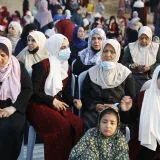 A group of women in hijabs pray together outdoors in the Gaza Strip, captured during daylight.