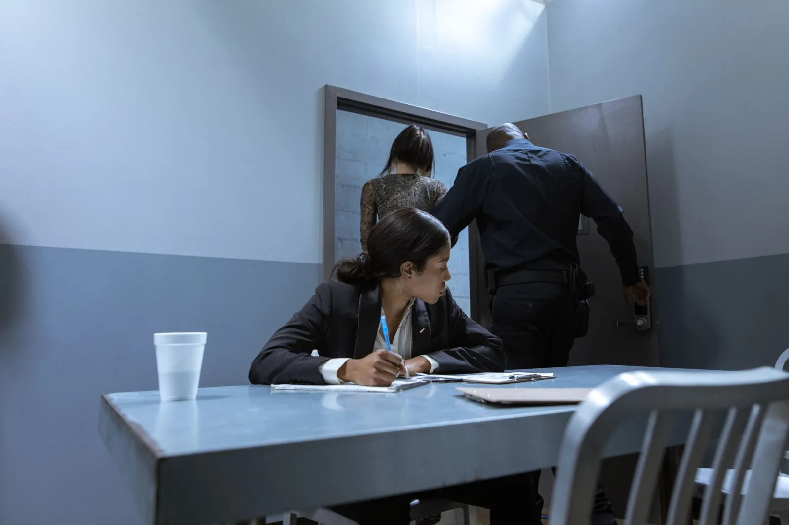 Un policía escolta al sospechoso mientras el abogado observa durante el interrogatorio.
