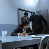 Un policía escolta al sospechoso mientras el abogado observa durante el interrogatorio.