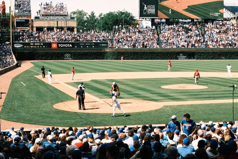 Vibrant scene of a baseball game at Wrigley Field with packed grandstands and players in action.