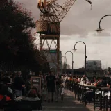 Lively street scene in Puerto Madero with a prominent crane and pedestrians enjoying the day.
