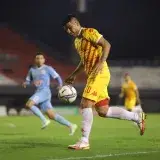 Soccer players in action during a competitive night match on a well-lit football field.