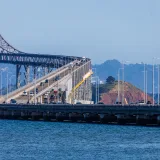 Vista del puente Richmond-San Rafael con vehículos cruzando sobre una masa de agua, rodeado de colinas.