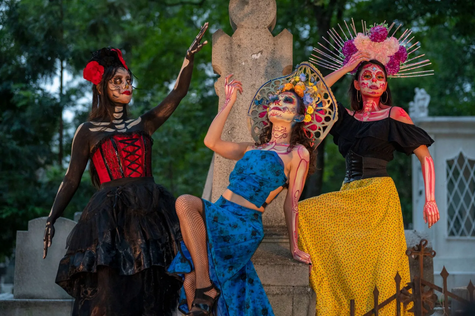 Vibrant Día de Muertos celebration featuring women in traditional Catrina attire at a cemetery.