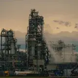 A detailed view of a refinery's towers against a cloudy dusk sky, showcasing industrial architecture.