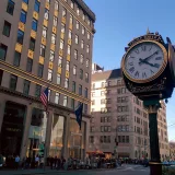 Vista de la calle de Nueva York que muestra una clásica torre del reloj contra la arquitectura urbana.