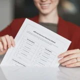 Una mujer sonriente sostiene una papeleta electoral durante la jornada de votación.