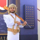 A man in traditional Yemeni dress poses with a rifle indoors in Sana'a, Yemen.