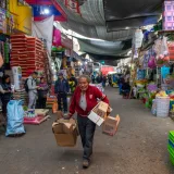 Animada escena de mercado callejero, con vendedores y clientes realizando transacciones comerciales.