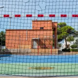 A vibrant sports field with a goal net under clear skies in El Perellonet, Spain.