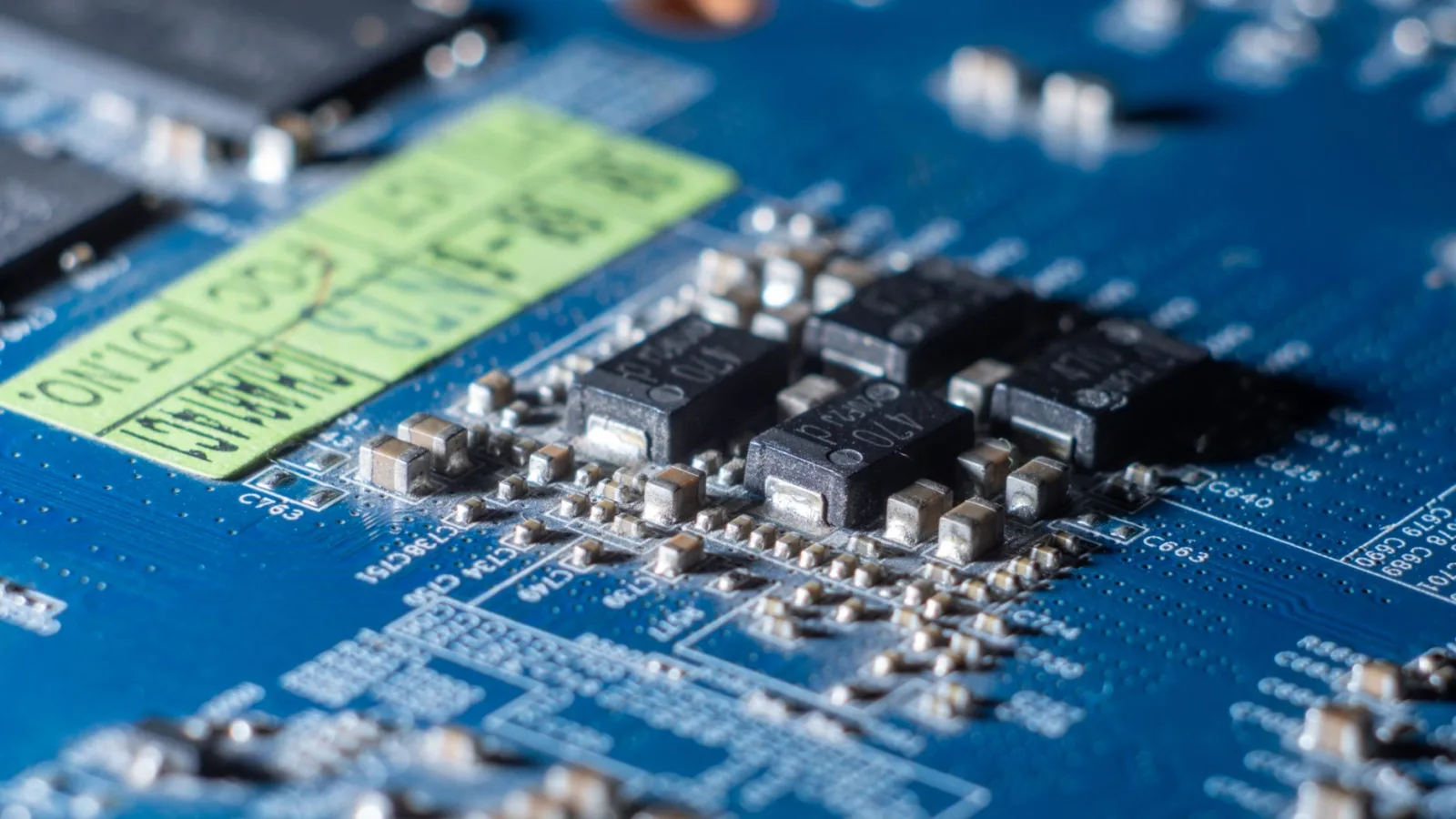 Primer plano detallado de una placa de circuitos azul con varios microchips y componentes electrónicos.