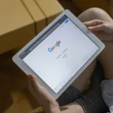 Primer plano de manos sosteniendo una tableta que muestra la página de búsqueda de Google.