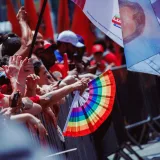 Protesta callejera dinámica en SP, Brasil con una vibrante exhibición de abanicos arcoíris.